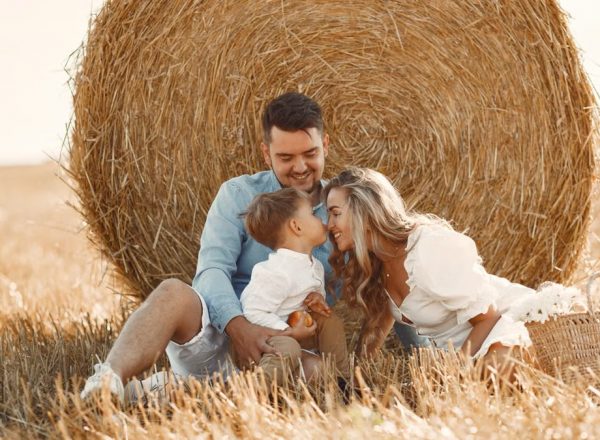 A happy family enjoying time together in a sunny, rural hay field, showcasing warmth and bonding.