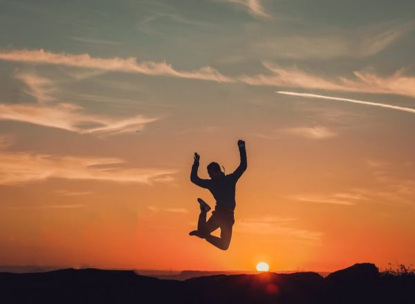 A person silhouetted against a stunning sunset, capturing a moment of freedom and joy.