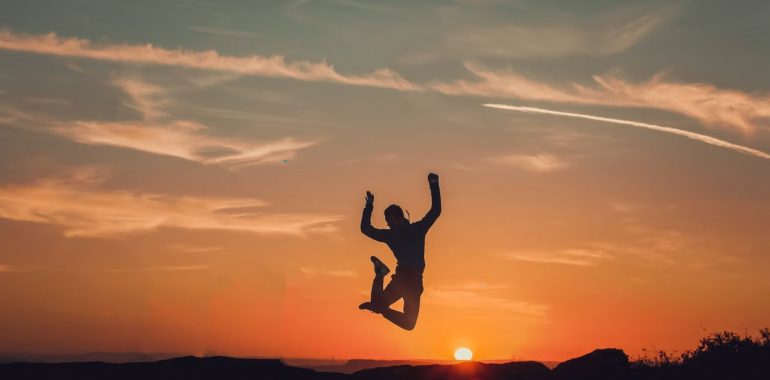 A person silhouetted against a stunning sunset, capturing a moment of freedom and joy.